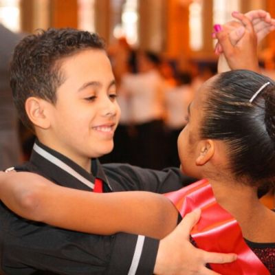 A young boy and girl are performing a ballroom dance.